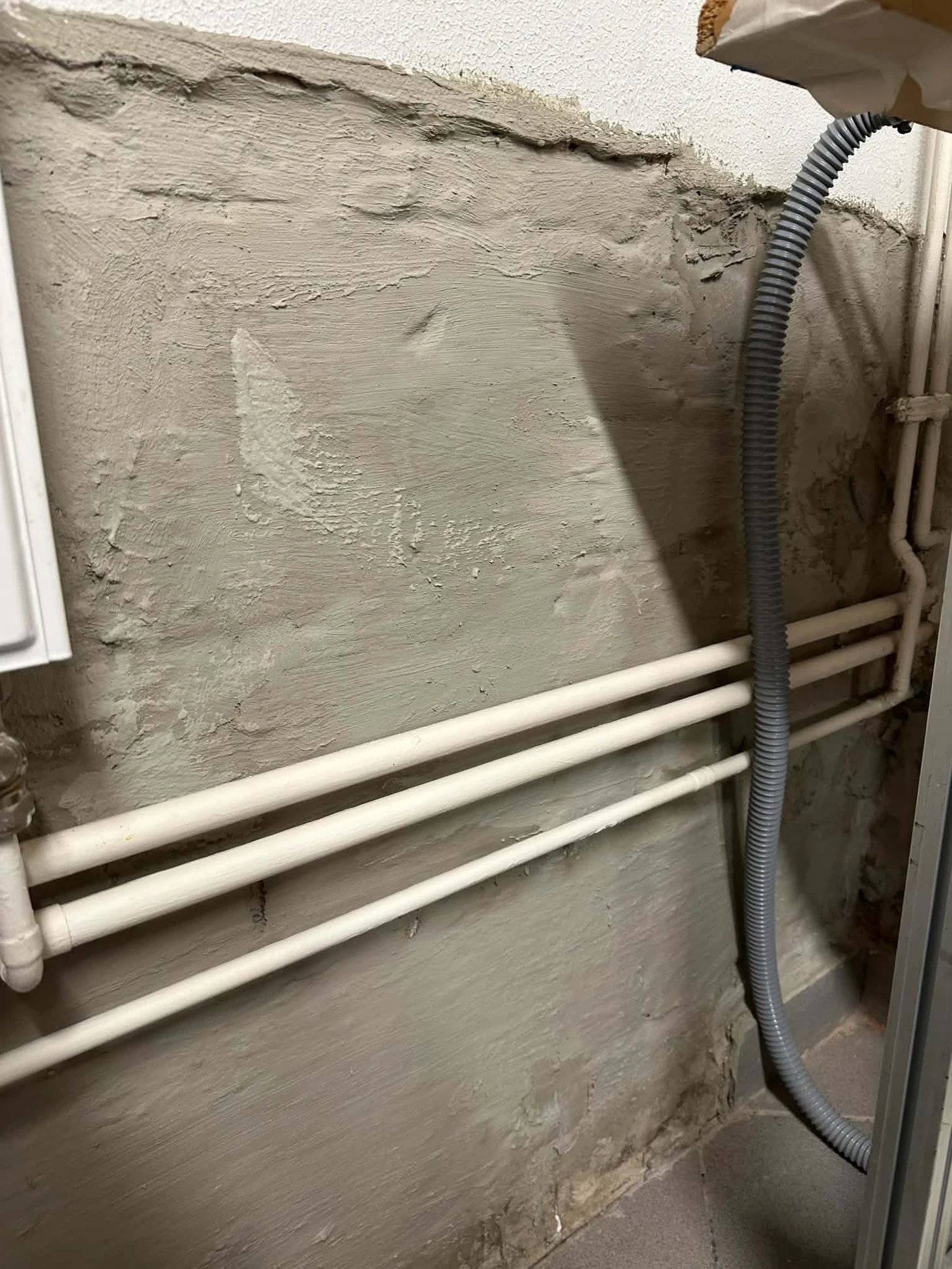 Pojedyncze ujęcie warstwy zabezpieczającej ścianę przy rurach instalacyjnych i przewodzie
